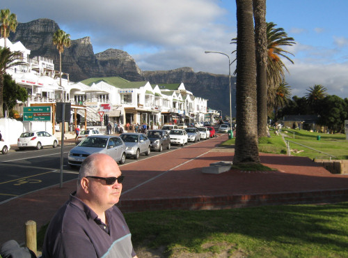 John sitting on a bench on the promenade at Camps Bay